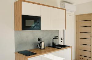 a kitchen with white cabinets and a coffee maker on a counter at Apartamenty Jordanów - Stacja Paliw MOYA in Jordanów