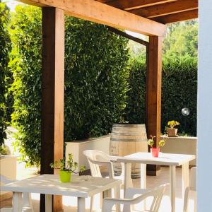two white tables and chairs under a wooden pergola at Casa Giulia in Niscemi