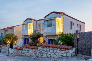 a house with a stone wall and a fence at Alacati Fora Bella in Alacati