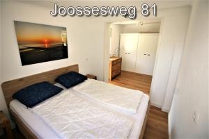 ヴェストカペレにあるJoossesweg 81のベッドと壁に絵が飾られた寝室