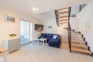 sala de estar con escalera y sofá azul en Apartamenty Sun Seasons 24 - Zaciszna, en Niechorze