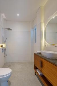 een badkamer met een wastafel, een toilet en een spiegel bij Villa Santosa Heights in Kuta Lombok