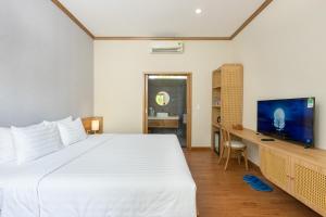 um quarto com uma grande cama branca e uma escrivaninha em Coco Garden Resort em Duong Dong