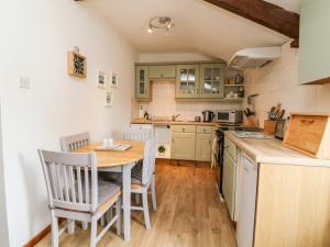 uma cozinha com uma mesa de madeira e cadeiras numa cozinha em Ash Cottage em Ilfracombe