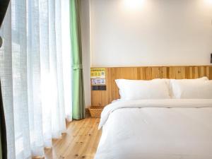 a bedroom with two beds and a window at Cloudy Warm Hotel - Huangshan Scenic Area Transfer Center Branch in Huangshan City