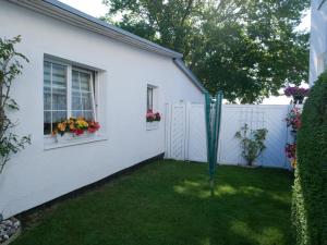 ein weißes Haus mit einem Zaun und einem Hof in der Unterkunft Bungalow Rarek "20 Gehmin vom Ostseestrand" in Bansin + 17 Fotos