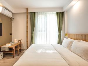 a bedroom with a bed and a table and a window at Cloudy Warm Hotel - Huangshan Scenic Area Transfer Center Branch in Huangshan City