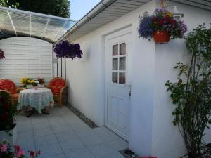 eine Terrasse mit einer weißen Tür und einem Tisch mit Blumen in der Unterkunft Bungalow Rarek "20 Gehmin vom Ostseestrand" in Bansin