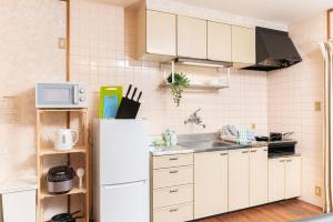 een keuken met een witte koelkast en een spoelbak bij 別府温泉 小倉の湯 in Beppu