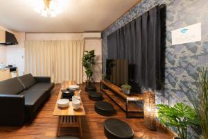 uma sala de estar com um sofá e uma televisão em HAKUDAKU no YUYA em Beppu