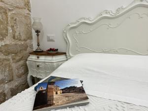 una camera da letto con un letto bianco e un libro sopra di Casa Tancredi a Scicli