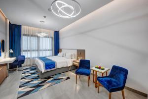 a hotel room with a bed and blue chairs at ABAR HOTEL APARTMENTS DIP-1 in Dubai +68 photos
