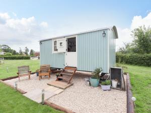 a green tiny house with chairs and a patio at Honeybee Lodge in Woodhall Spa