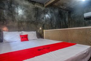 um quarto com uma cama com um cobertor vermelho em RedDoorz near Jumbo Mall Sragen em Sragen