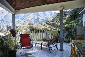 a patio with chairs and a view of mountains at Vétiver in Cilaos