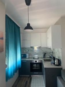 uma cozinha com armários brancos e uma cortina azul em Verona Apartment em Sandanski
