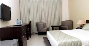 a hotel room with a bed and a tv and chairs at The Townhall (Unit of Prohotel) in Chennai