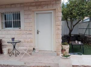 a white front door of a house with a table at דירה ירוקה על הנחל in Qiryat Shemona
