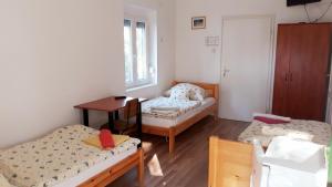 a room with two beds and a table and a desk at Boglár-Coop Üdülő in Balatonboglár