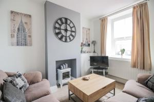 a living room with a couch and a table and a clock at Billy's Cottage in Maryport