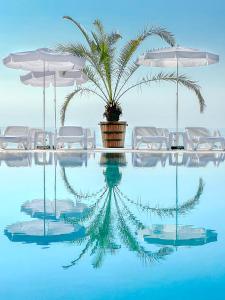 a pool with chairs and a palm tree and umbrellas at Moko Beach managed by Grifid - 24 Hours Ultra All Inclusive & Private Beach in Golden Sands