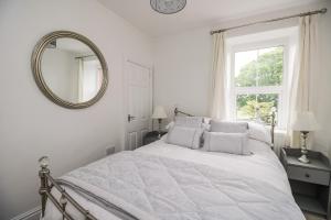 a white bedroom with a bed and a mirror at Billy's Cottage in Maryport
