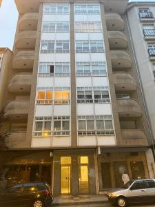 two cars parked in front of a tall building at Apartamento Couto in Ribadeo