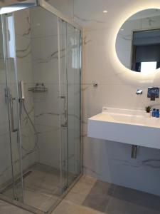 ein Bad mit einer Glasdusche und einem Waschbecken in der Unterkunft Flâneur apartments in Ormos Panagias
