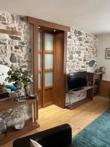 a living room with a tv and a stone wall at Charmant appartement, centre piéton Vieille Ville Annecy in Annecy