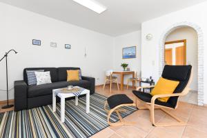 a living room with a black couch and chairs at Ferienwohnung Nordseebutze in Esens
