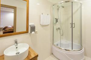 a bathroom with a glass shower and a sink at Sunset Hotel in Jūrmala