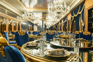 uma sala de jantar com mesas, cadeiras e lustres em Prezident Palace Belgrade - Adults Only em Belgrado