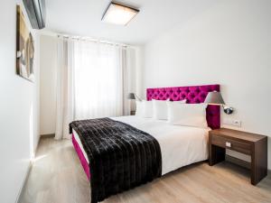 - une chambre avec un grand lit et une tête de lit violette dans l'établissement Centrum Superior Suites, à Białystok