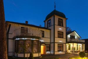 a large white building with a tower at Sunset Hotel in Jūrmala