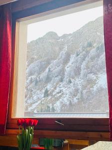 una finestra con fiori rossi di fronte a una montagna di Foemina a Faidello