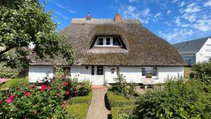 a thatched house with a window and flowers at Reetdachtraum in Middelhagen