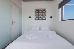 a white bed in a white room with an iphone at Apartment With Terrace In Piraeus in Piraeus