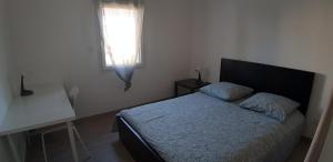 een slaapkamer met een bed, een bureau en een raam bij Maison neuve 66 bis in Saint-Martin-la-Rivière