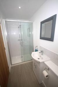 a white bathroom with a shower and a sink at No 28D St Benedict in Glastonbury