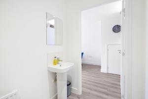 uma casa de banho branca com um lavatório e um espelho em Modern 5 Bedroom 3 Bathroom Serviced House Aylesbury with parking By 360Stays em Aylesbury