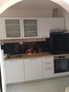 Apartment Marija Marina في مارينا: مطبخ أبيض مع دواليب بيضاء ومغسلة