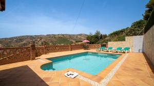 uma piscina com cadeiras e um deque com uma montanha em Villa Fuente Luz Frigiliana by Ruralidays em Frigiliana