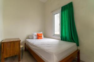 1 dormitorio pequeño con cortina verde y cama en KoolKost Syariah near LRT Boulevard Selatan Station - Minimum Stay 6 Nights en Yakarta