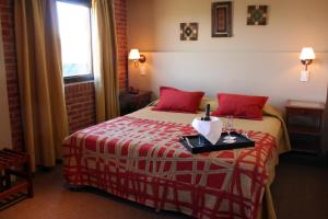 Habitación de hotel con cama con almohadas rojas en Hosteria Posta Sur en El Calafate