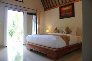 een slaapkamer met een groot bed en een groot raam bij Penida Bay Village in Nusa Penida