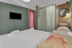 1 dormitorio con 2 camas y TV en la pared en Romantic stone house/City center/Beach!, en Makarska