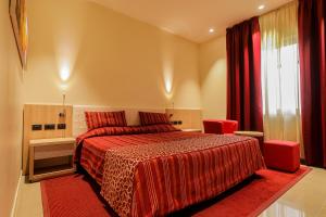 a bedroom with a bed with red sheets and a window at Heliconia Park Port Harcourt Hotel and Suites in Port Harcourt