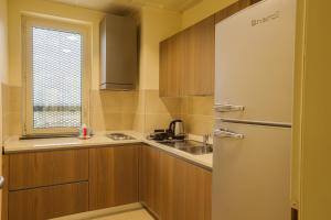 a small kitchen with a refrigerator and a window at Heliconia Park Port Harcourt Hotel and Suites in Port Harcourt