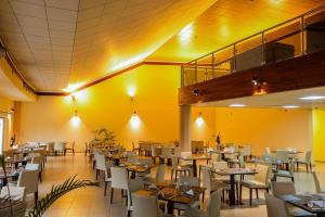 a restaurant with tables and chairs and yellow walls at Heliconia Park Port Harcourt Hotel and Suites in Port Harcourt