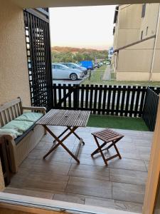 um pátio com um banco e uma mesa na varanda em Joli appartement proche océan et centre ville em Lacanau